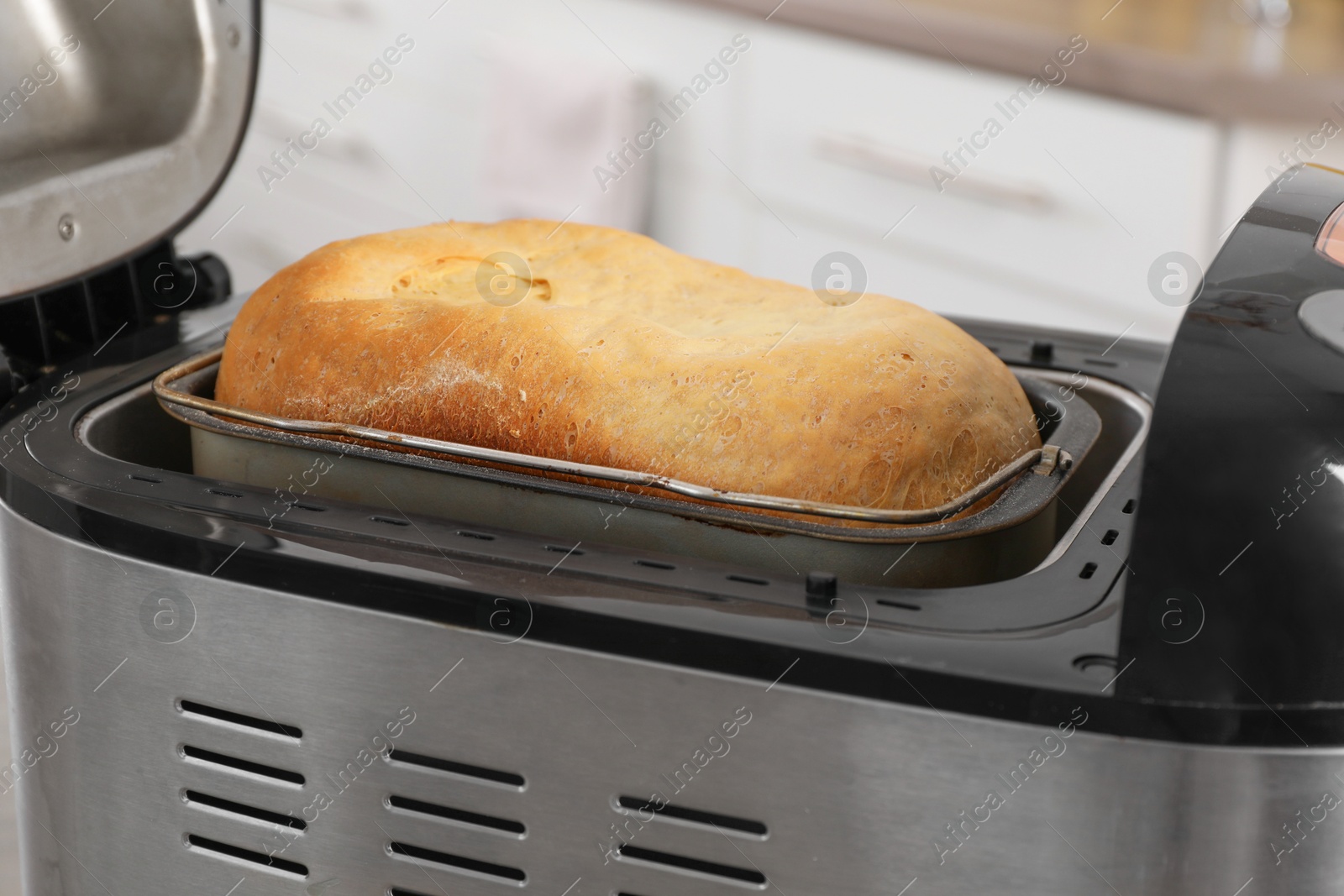 Photo of Fresh homemade bread in open breadmaker machine, closeup