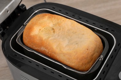 Photo of Fresh homemade bread in open breadmaker machine, closeup