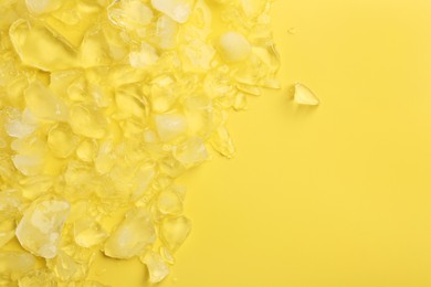 Pile of crushed ice on yellow background, top view. Space for text