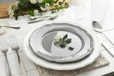 Stylish setting with cutlery, glasses and plates on white wooden table