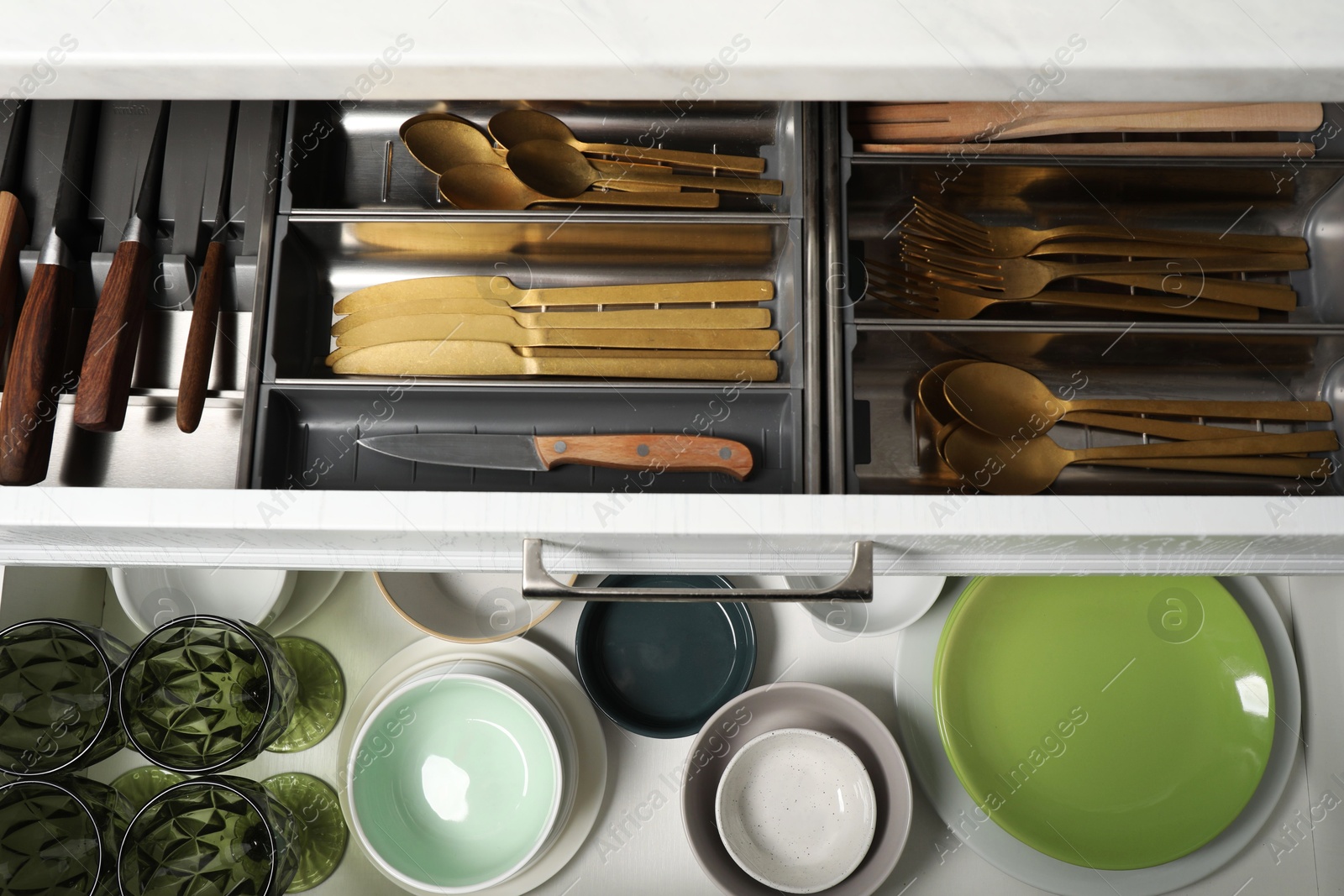 Photo of Ceramic dishware and cutlery in drawers indoors, top view