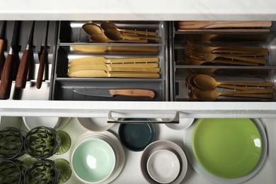 Photo of Ceramic dishware and cutlery in drawers indoors, top view