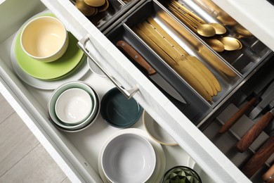 Ceramic dishware and cutlery in drawers indoors, above view