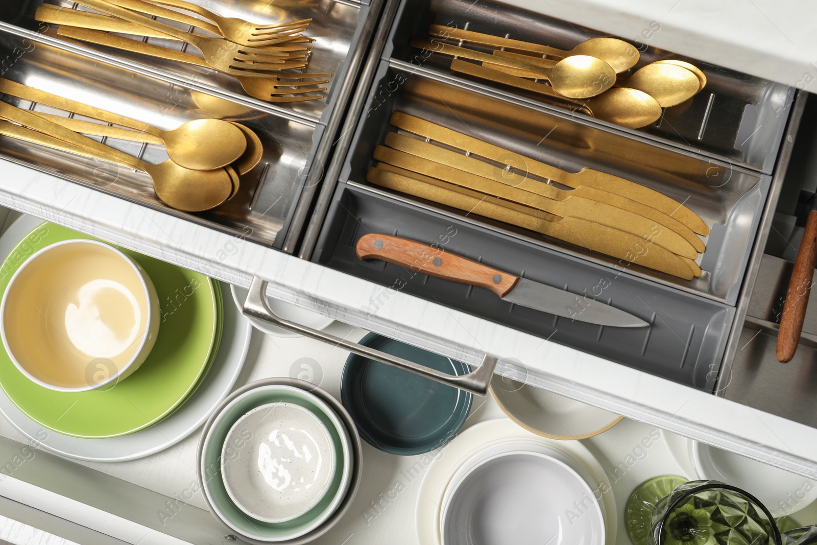 Photo of Ceramic dishware and cutlery in drawers indoors, top view