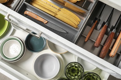 Ceramic dishware and cutlery in drawers indoors, above view