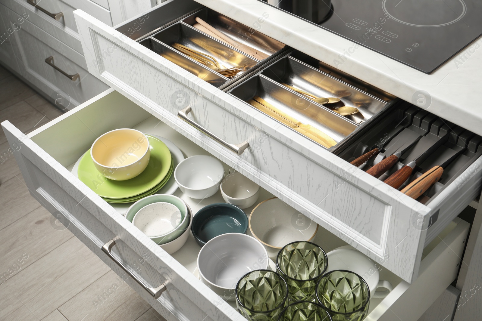 Photo of Ceramic dishware and cutlery in drawers indoors