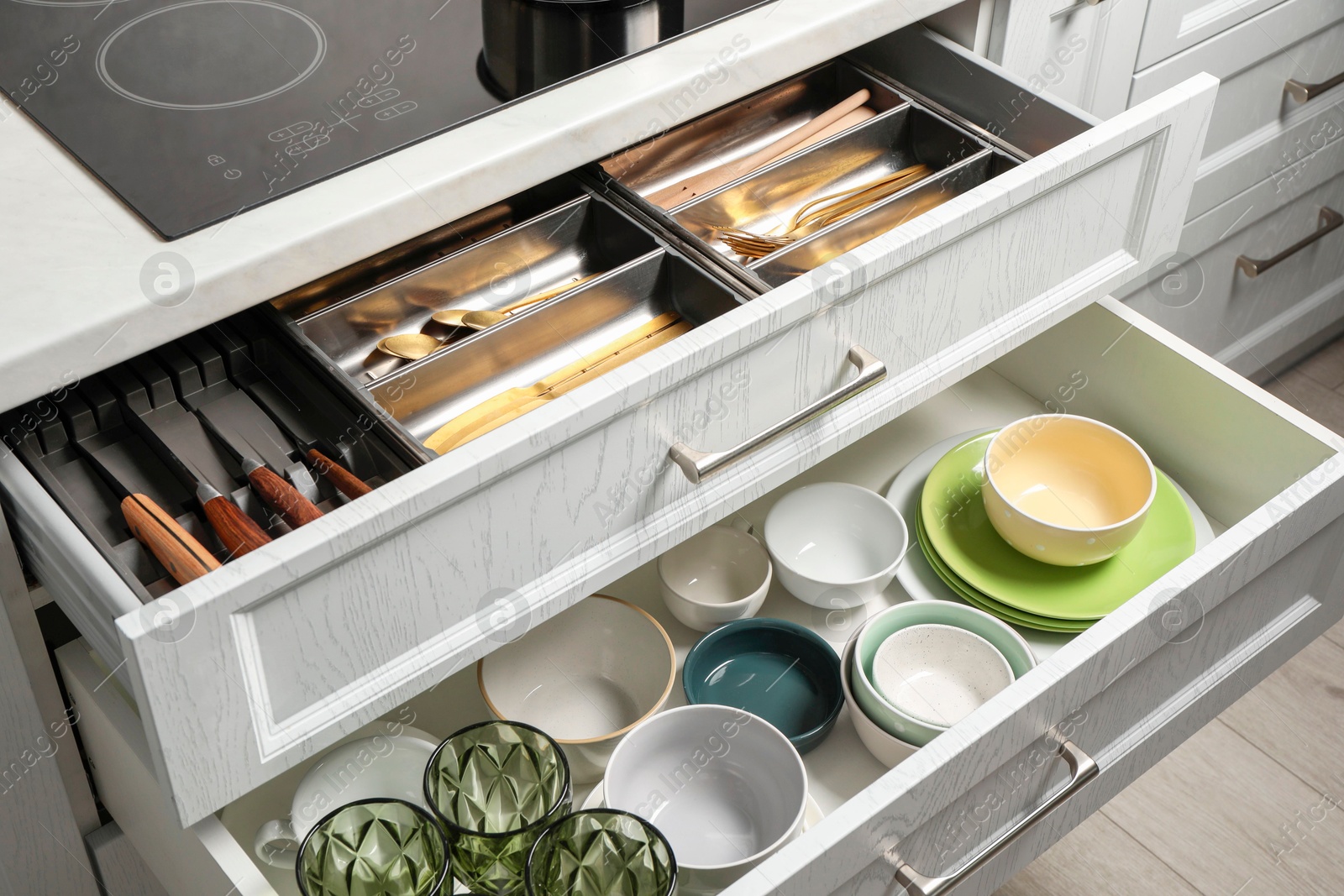 Photo of Ceramic dishware and cutlery in drawers indoors