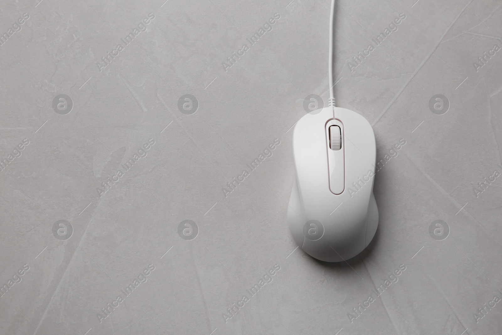 Photo of One wired mouse on grey textured table, top view. Space for text