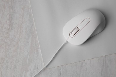 Photo of Wired mouse with mousepad on grey wooden table, top view. Space for text