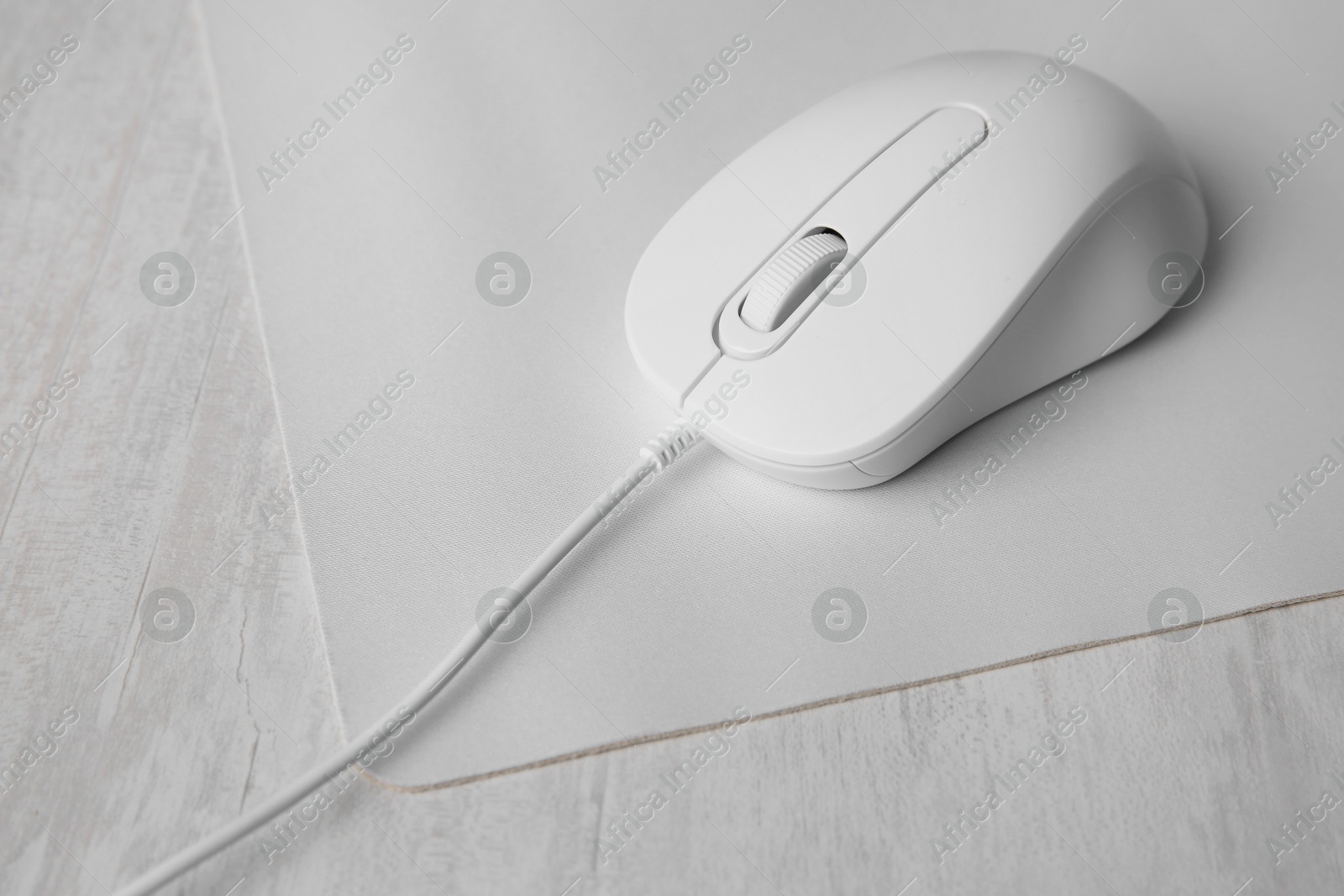 Photo of Wired mouse with mousepad on grey wooden table, closeup