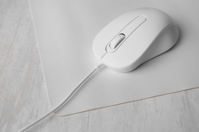 Photo of Wired mouse with mousepad on grey wooden table, closeup