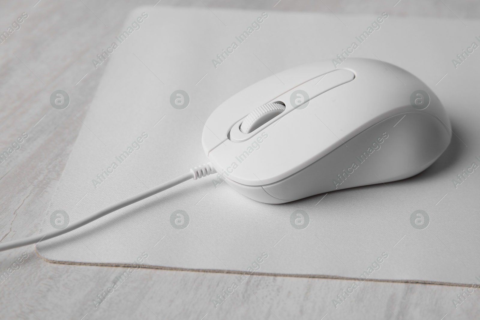 Photo of Wired mouse with mousepad on grey wooden table, closeup