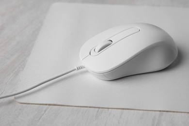 Wired mouse with mousepad on grey wooden table, closeup