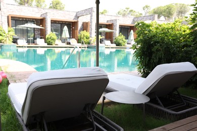 Photo of Sunbeds near outdoor swimming pool at luxury resort