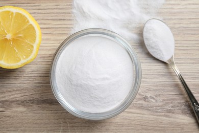 Photo of Baking soda and lemon on wooden table, top view