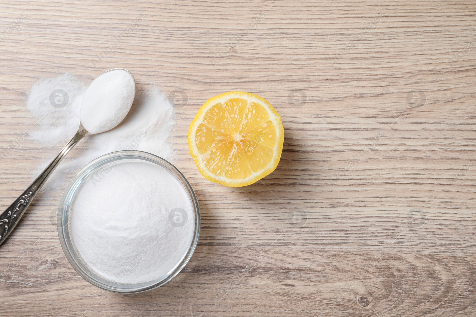 Photo of Baking soda and lemon on wooden table, top view. Space for text