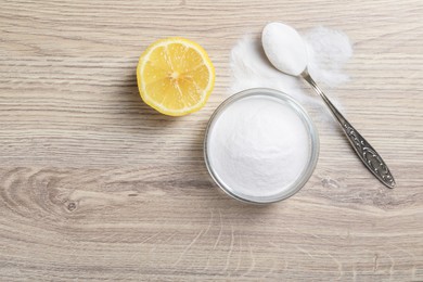 Photo of Baking soda and lemon on wooden table, top view. Space for text