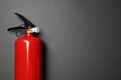 Photo of One red fire extinguisher on gray background, top view. Space for text