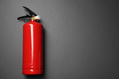 Photo of One red fire extinguisher on gray background, top view. Space for text