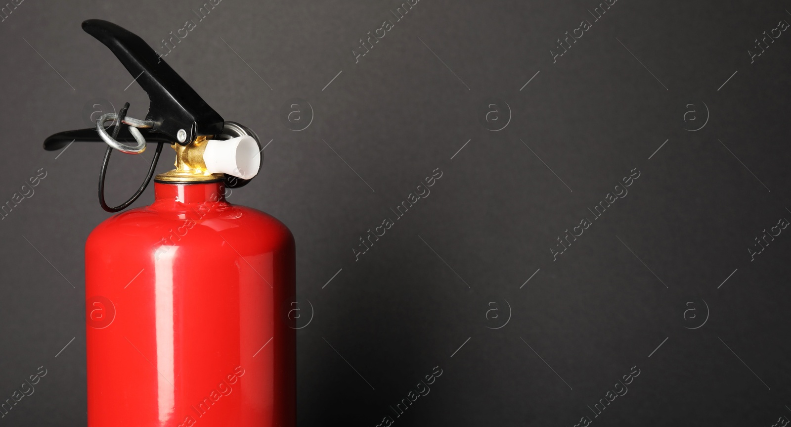 Photo of One red fire extinguisher on dark gray background, space for text