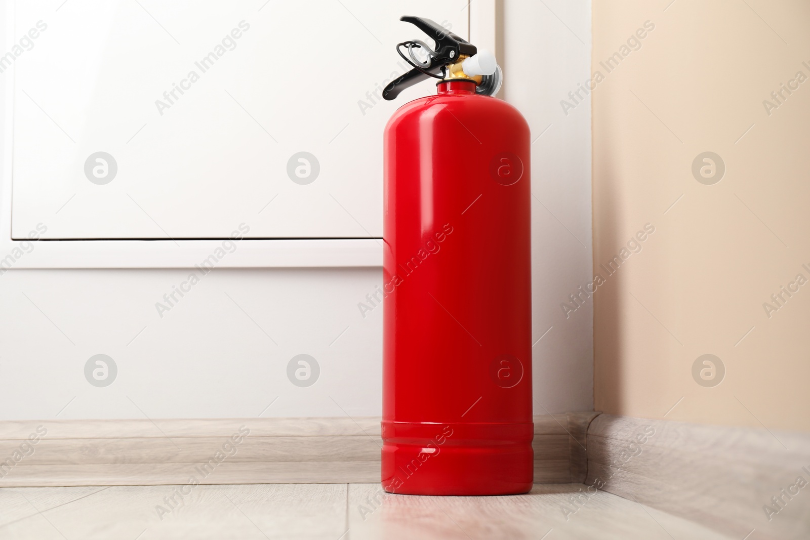 Photo of Fire extinguisher on floor indoors. Safety equipment