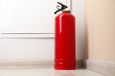 Photo of Fire extinguisher on floor indoors. Safety equipment