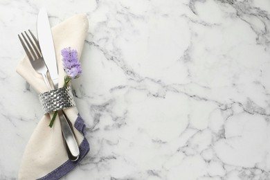 Stylish setting with cutlery and napkin on white marble table, top view. Space for text