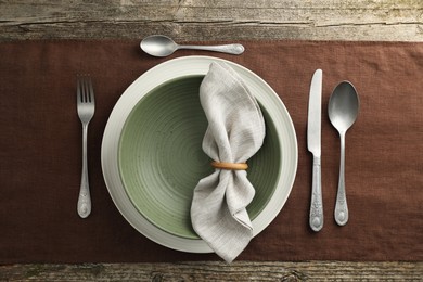 Stylish setting with cutlery, plate and bowl on wooden table, flat lay