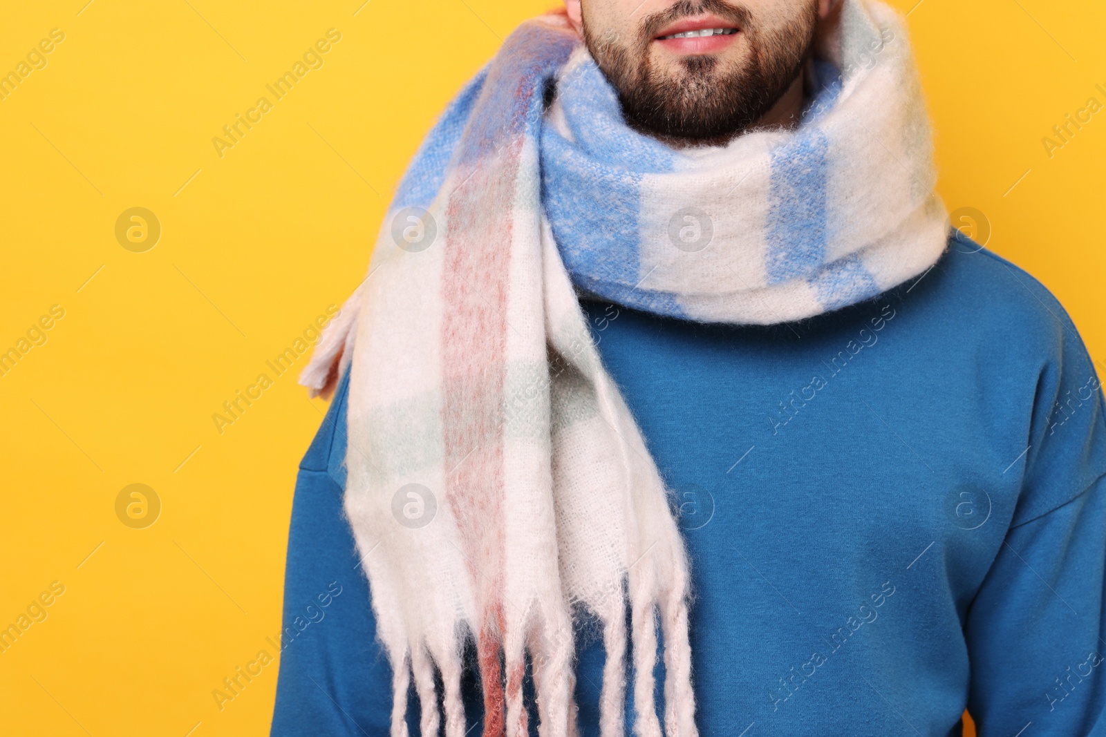 Photo of Man in warm scarf on yellow background, closeup