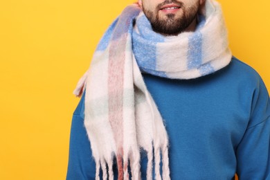 Man in warm scarf on yellow background, closeup