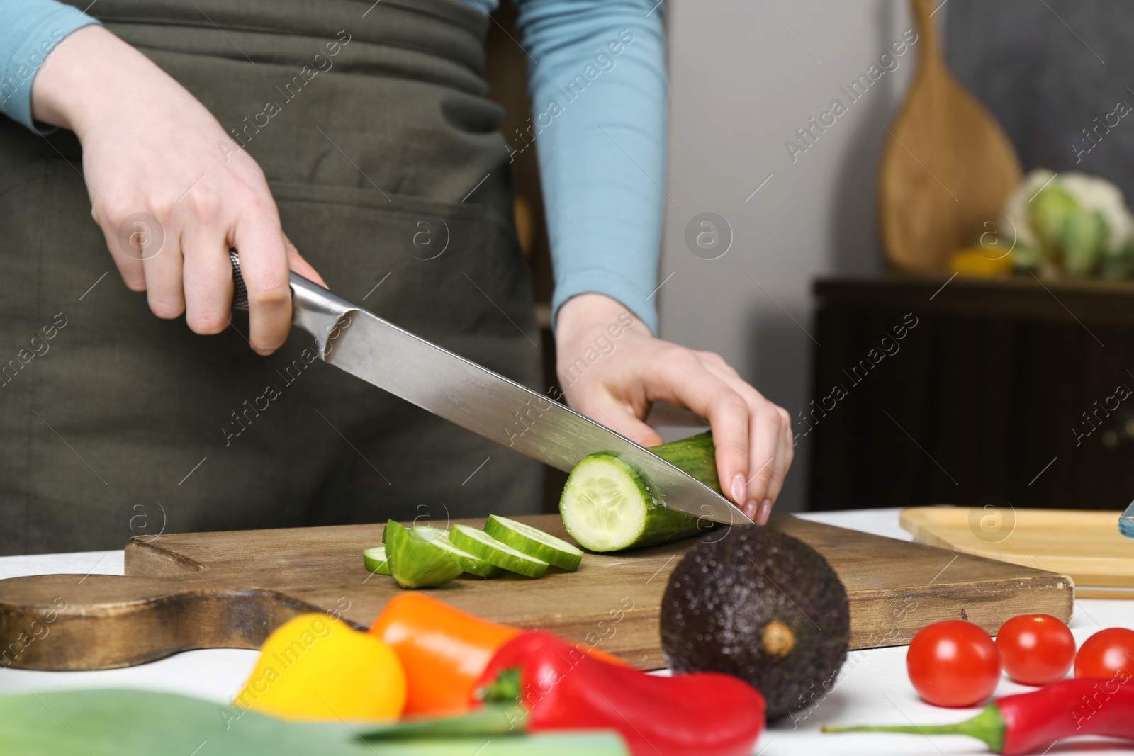 Photo of Healthy food. Woman cutting cucumber at white table, closeup