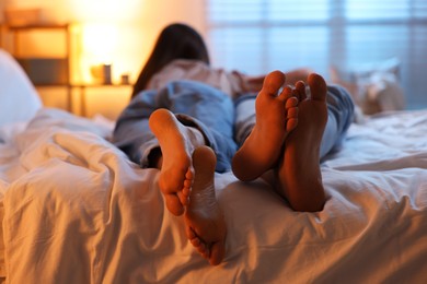 Couple enjoying each other on bed indoors at night, selective focus