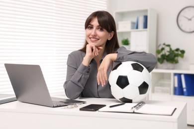 Photo of Smiling employee with soccer ball at table in office