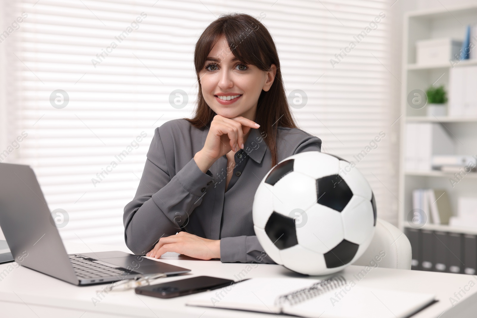 Photo of Smiling employee with soccer ball at table in office