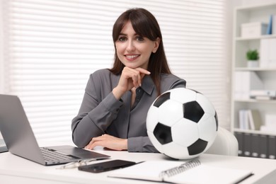 Smiling employee with soccer ball at table in office