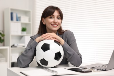 Smiling employee with soccer ball at table in office