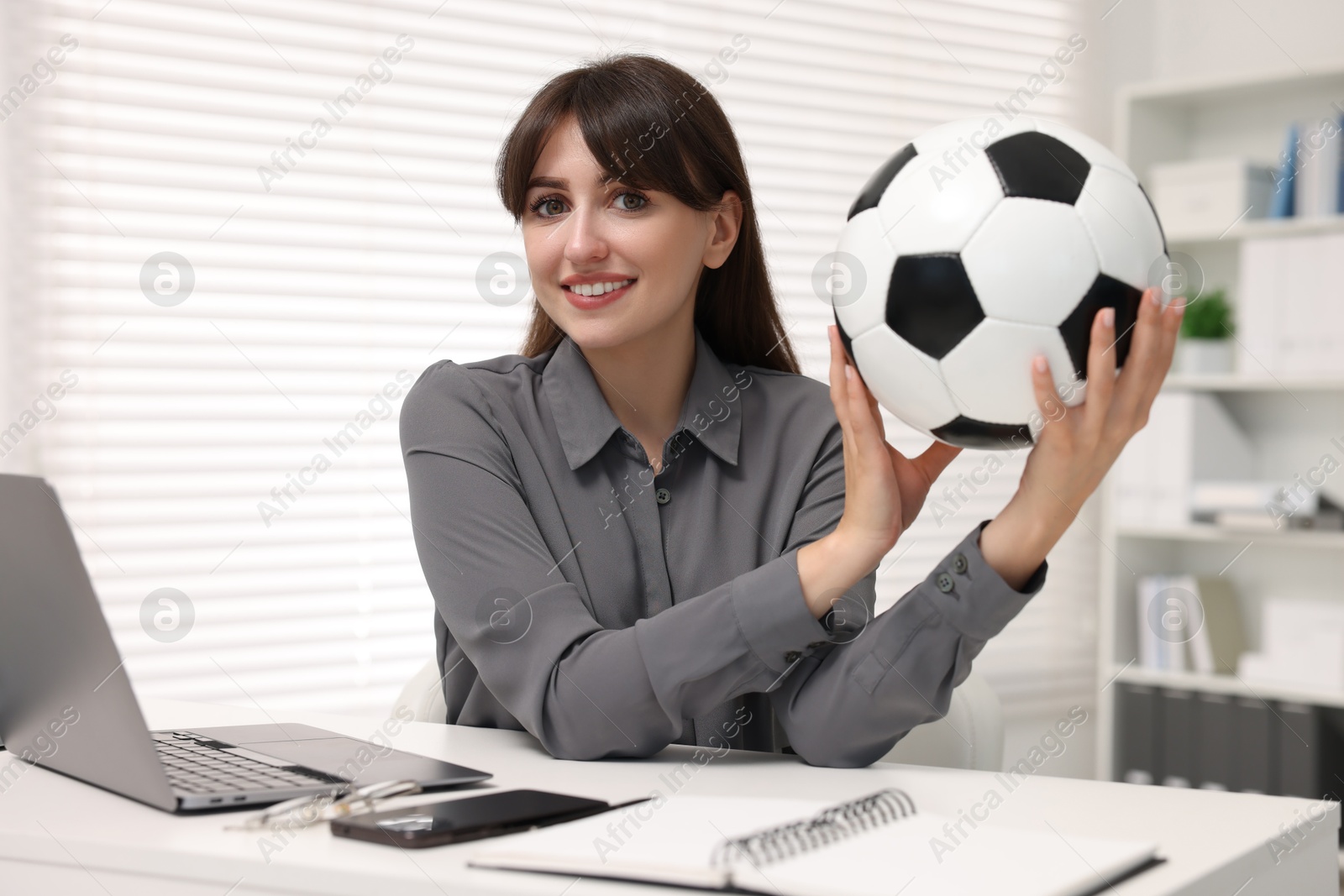 Photo of Smiling employee with soccer ball at table in office