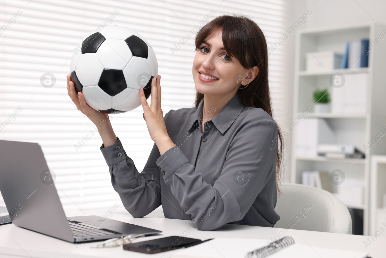 Photo of Smiling employee with soccer ball at table in office