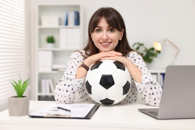 Smiling employee with soccer ball at table in office