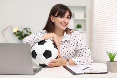 Photo of Smiling employee with soccer ball at table in office