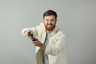 Photo of Happy man playing video game with controller on grey background