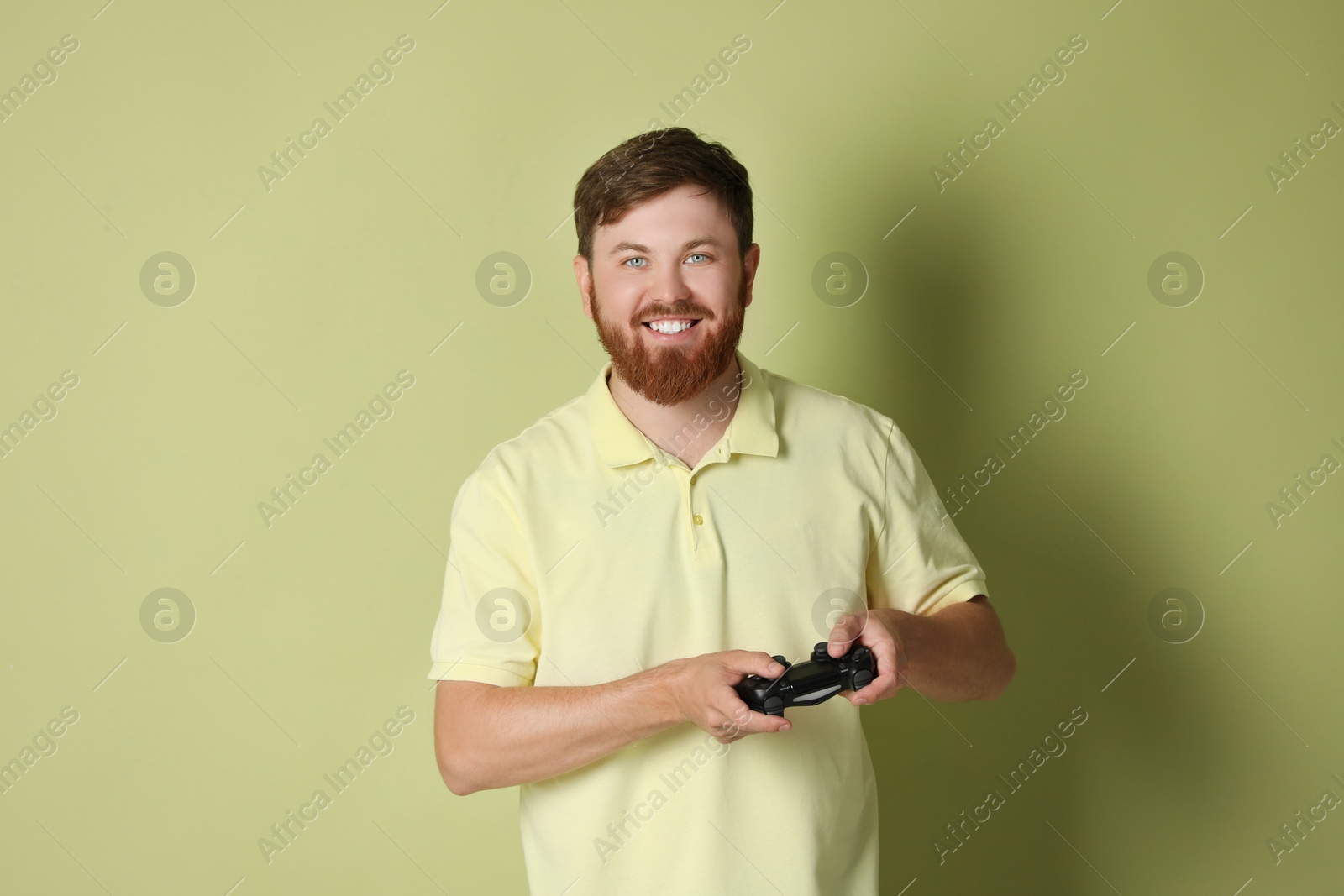 Photo of Happy man with game controller on pale green background