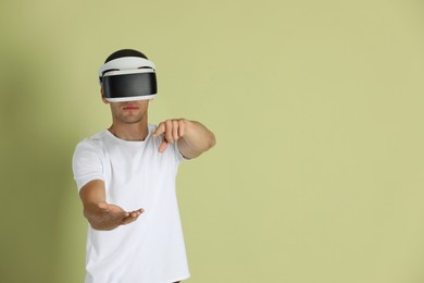 Man using virtual reality headset on light green background, space for text