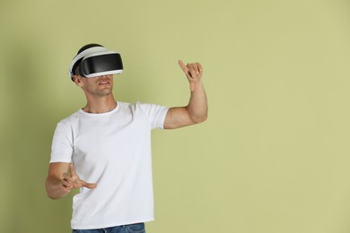Man using virtual reality headset on light green background, space for text