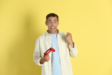 Happy man with controller on yellow background