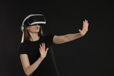 Surprised woman using virtual reality headset on black background