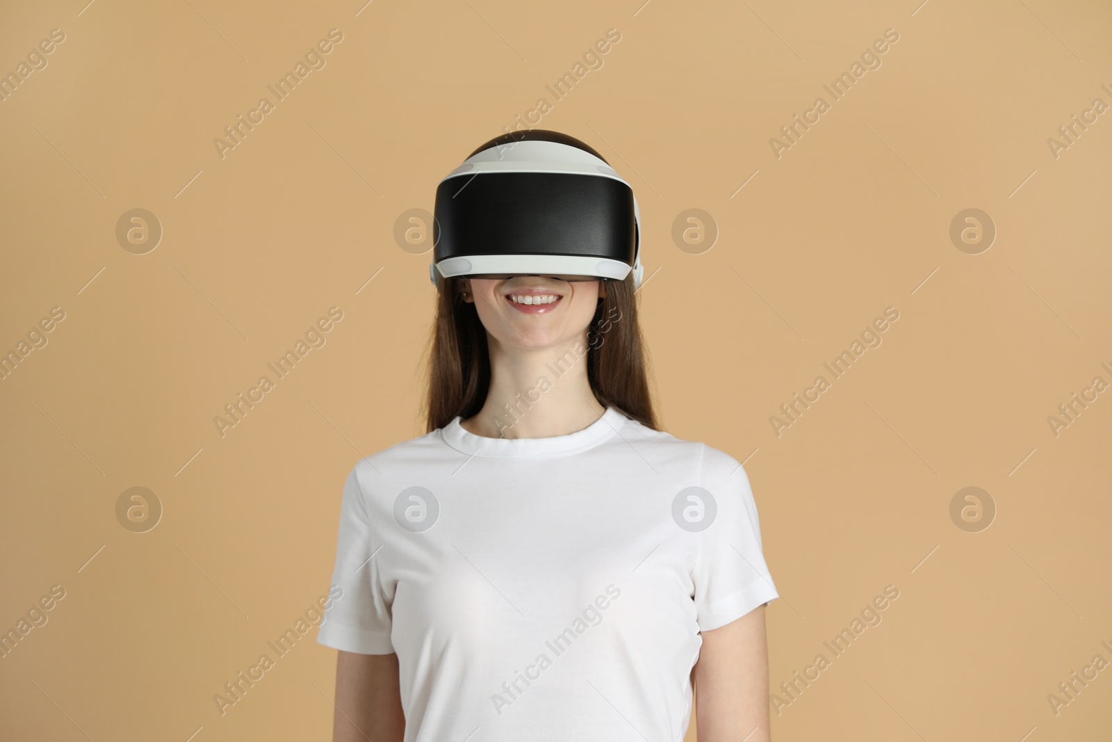 Photo of Smiling woman using virtual reality headset on beige background