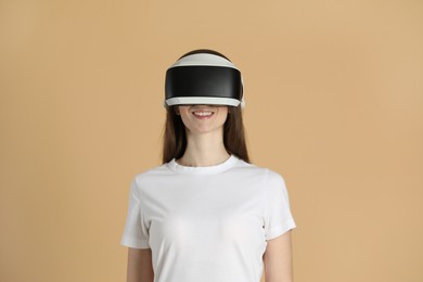 Smiling woman using virtual reality headset on beige background