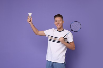 Photo of Young man with badminton racket and shuttlecock on purple background