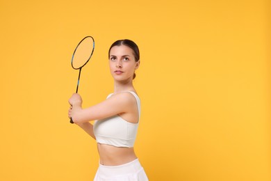 Young woman with badminton racket on orange background, space for text